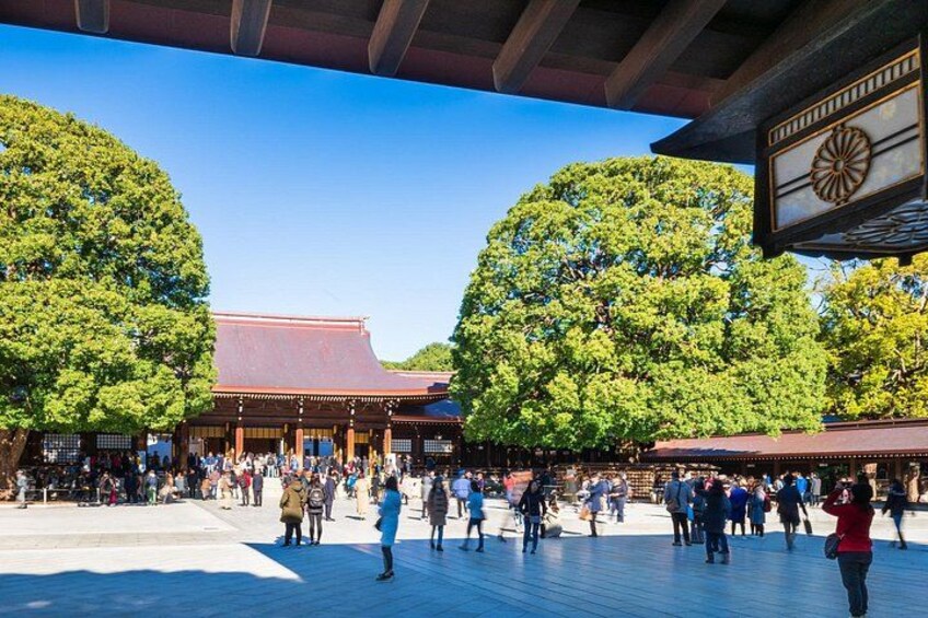 Een traditioneel Japans gebouw met een rood dak, omringd door grote bomen en een menigte mensen. 1