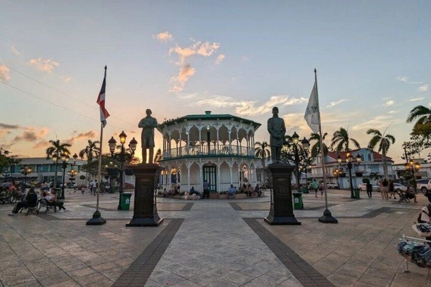 A plaza with a gazebo, statues, and flags. 2