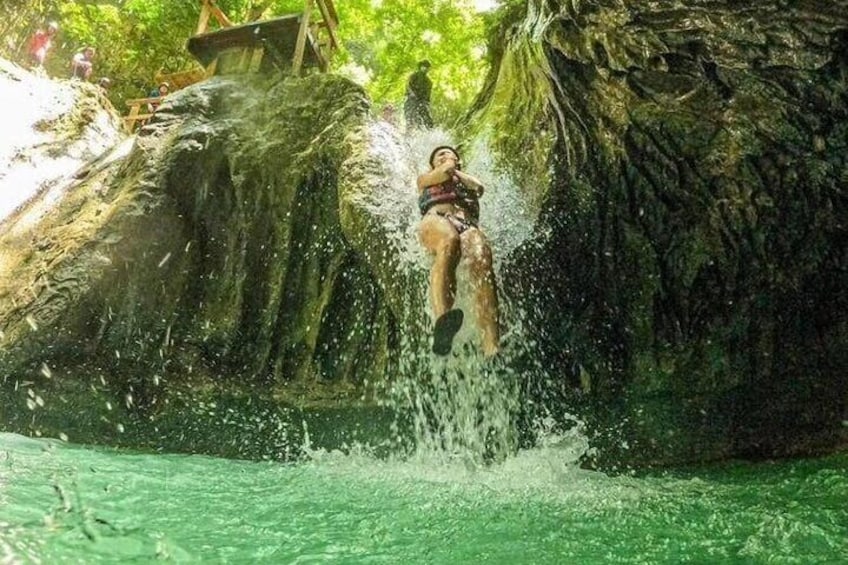 Une personne qui saute d’une falaise dans une étendue d’eau entourée d’arbres. 5