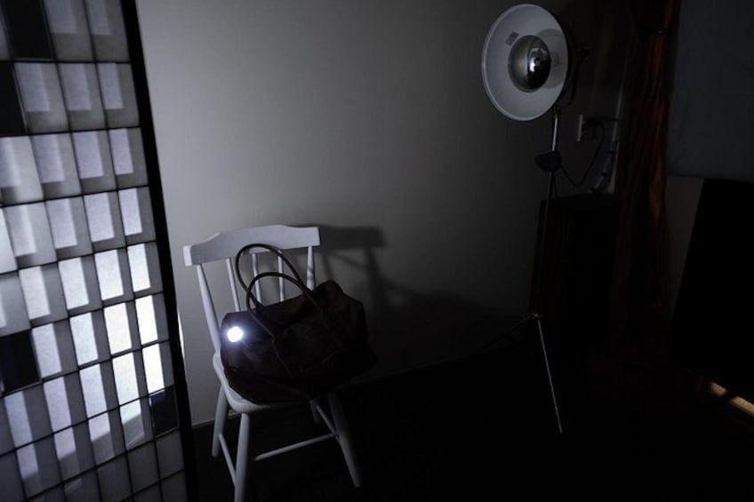 Una silla, un bolso, una lámpara de pie y una ventana con persianas. 2
