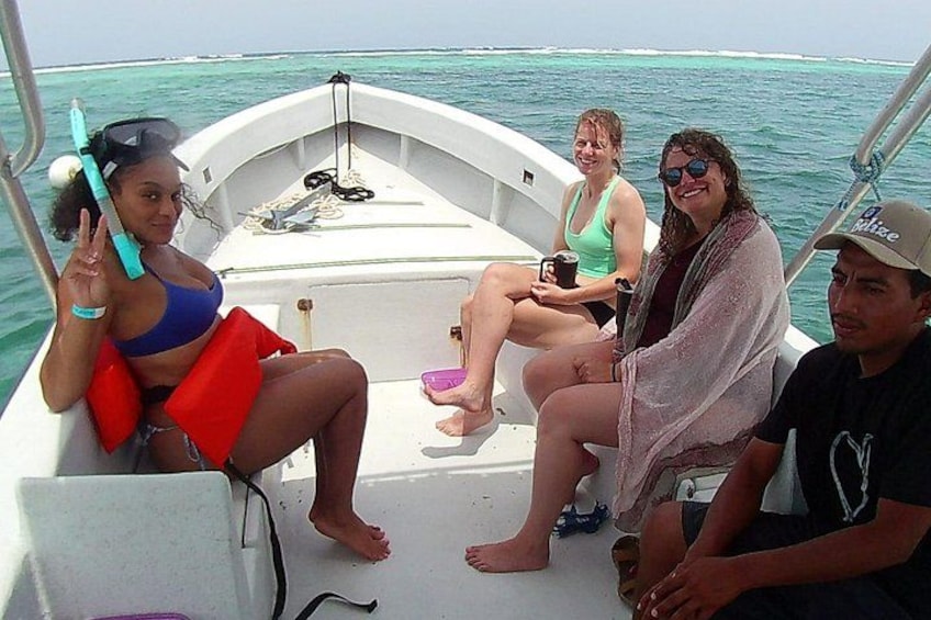 A boat with four people on board, one person holding a snorkel, and the ocean in the background. 2