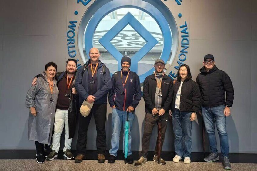 Un grupo de personas de pie frente a un letrero con un logotipo circular y el texto "WORLD EMONDIAL". 4