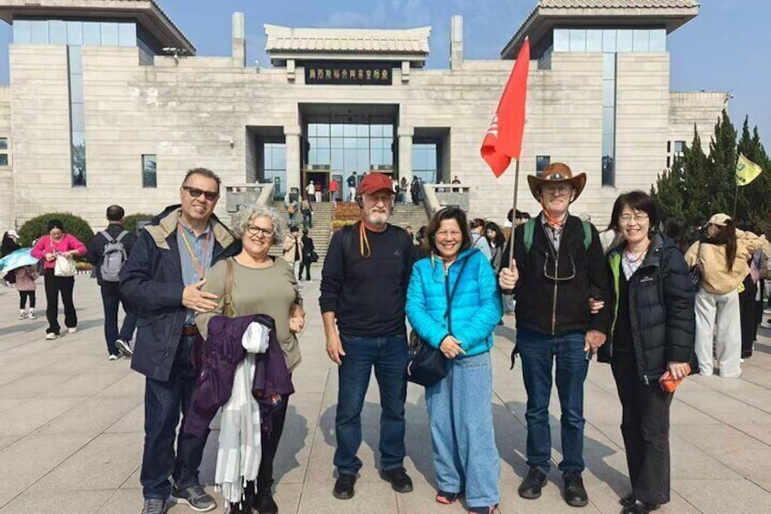 Un grupo de personas de pie frente a un edificio con una bandera roja. 2