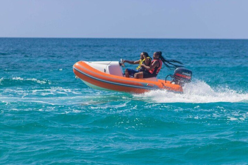 Een klein oranje opblaasbaar bootje met twee personen op het water. 5