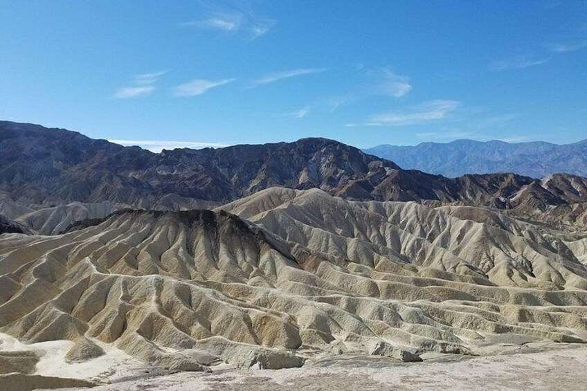 Paisaje desértico con formaciones rocosas estratificadas y montañas distantes bajo un cielo despejado. 4