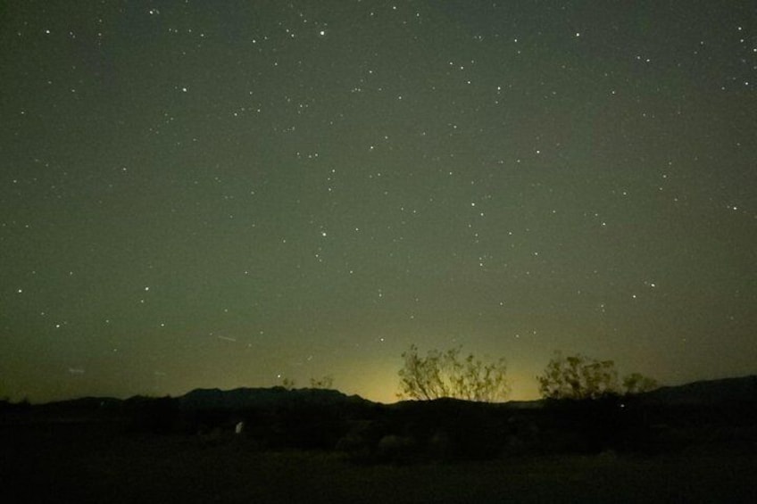 Un cielo nocturno estrellado sobre un paisaje montañoso con vegetación escasa. 2