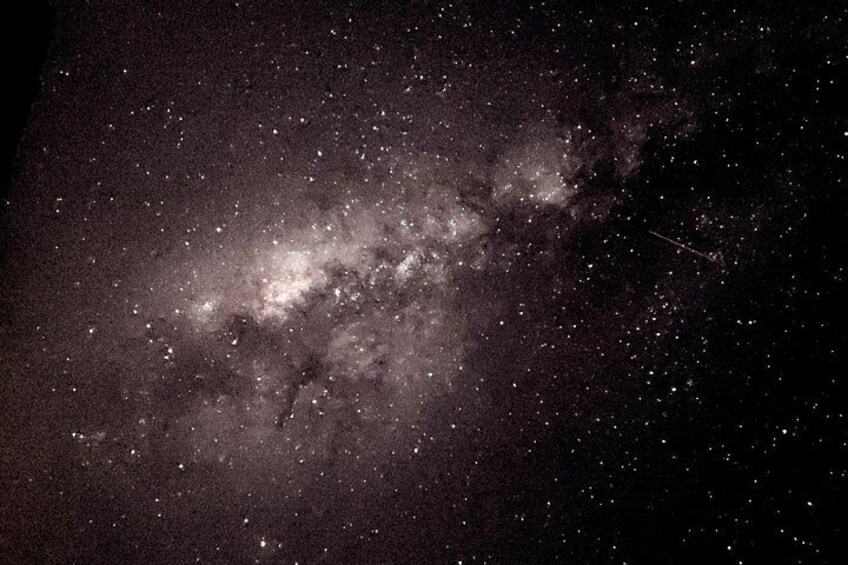 A starry night sky with a dense cluster of stars and a faintly visible galaxy. 3