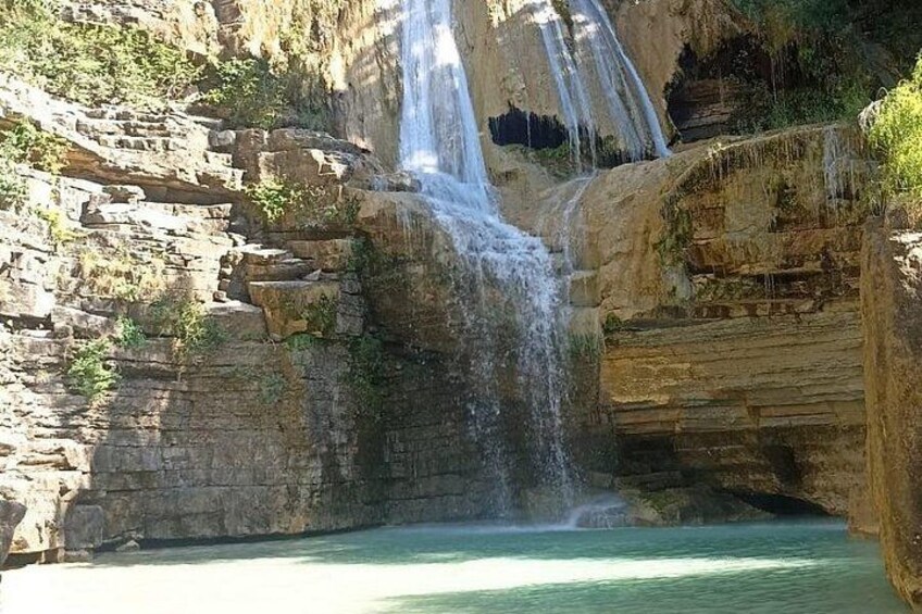 A waterfall cascading into a pool surrounded by rocky cliffs. 2