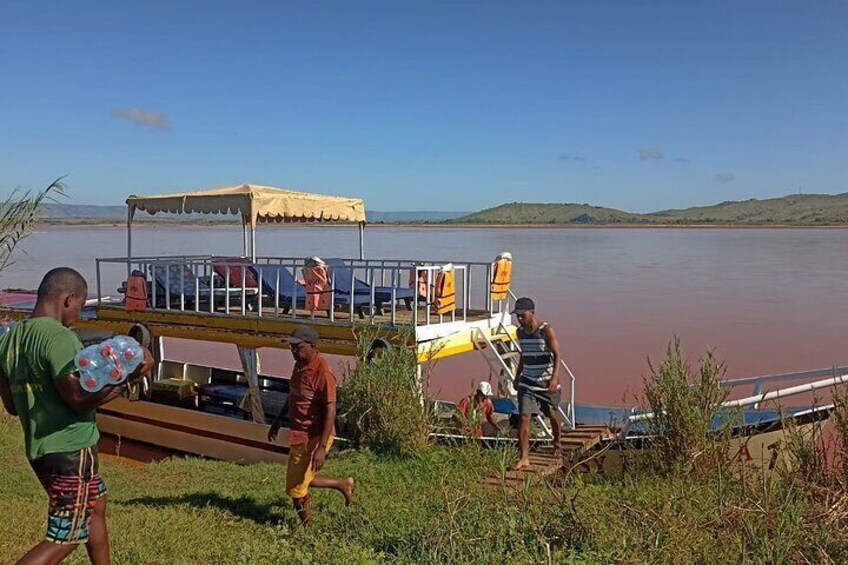 A group of people near a boat on a river with a canopy. 5