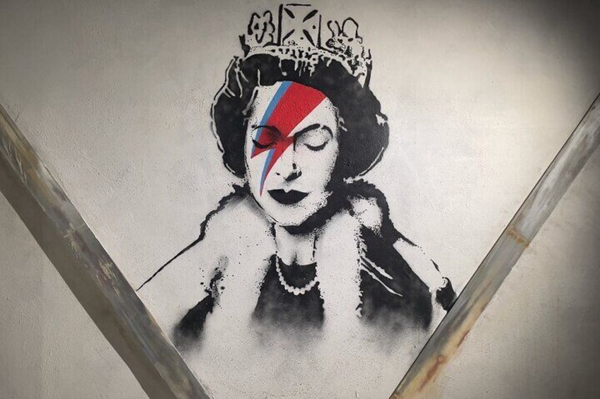 A graffiti mural of a woman with a crown and a red and blue flag on her head. 4