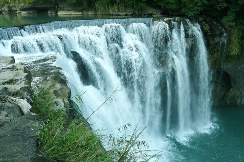 A multi-tiered waterfall cascading over rocks into a body of water. 4