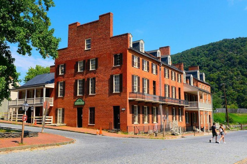 A red brick building with a balcony, a street sign, and a person walking. 4