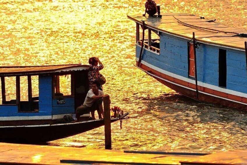 A boat with a person standing on the dock, another person on the boat, and a calm water body. 1