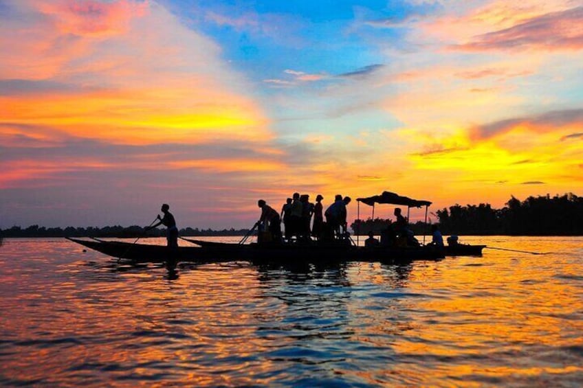 A sunset over a body of water with people on a boat. 1