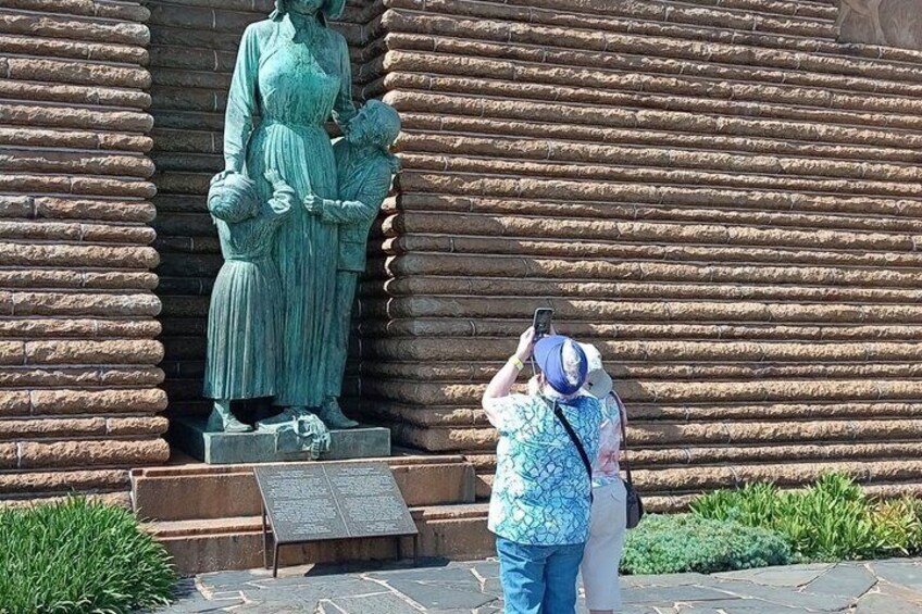 A statue of a woman holding a child in front of a stone wall. 3