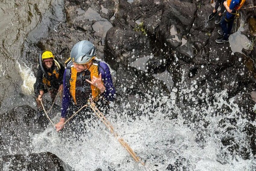 Dos personas descendiendo por una pared rocosa haciendo rappel. 2