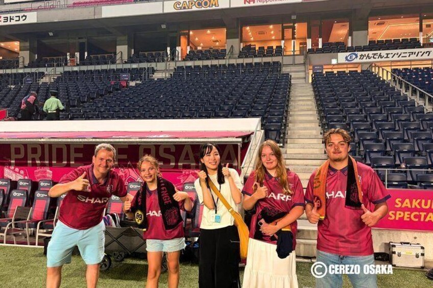 A group of people in a stadium with a banner reading 'PRIDE SAKURA'. 4