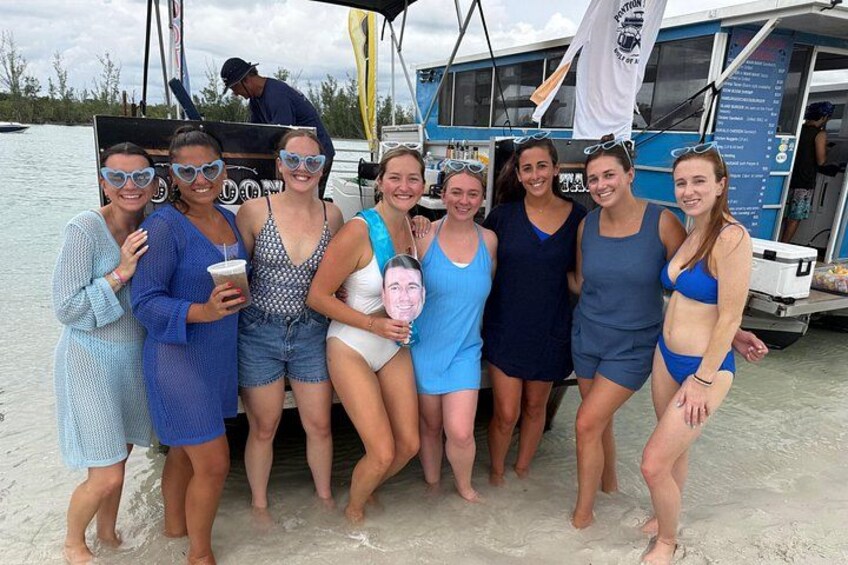 A group of people on a boat with a beach and water in the background. 5