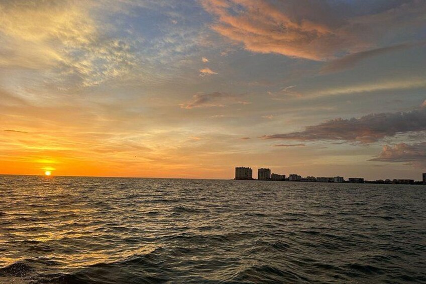 A sunset over a body of water with buildings in the distance. 2