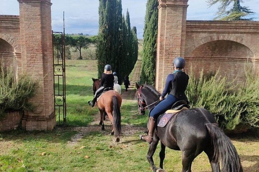 Two riders on horses, a brick archway, and a gate. 2