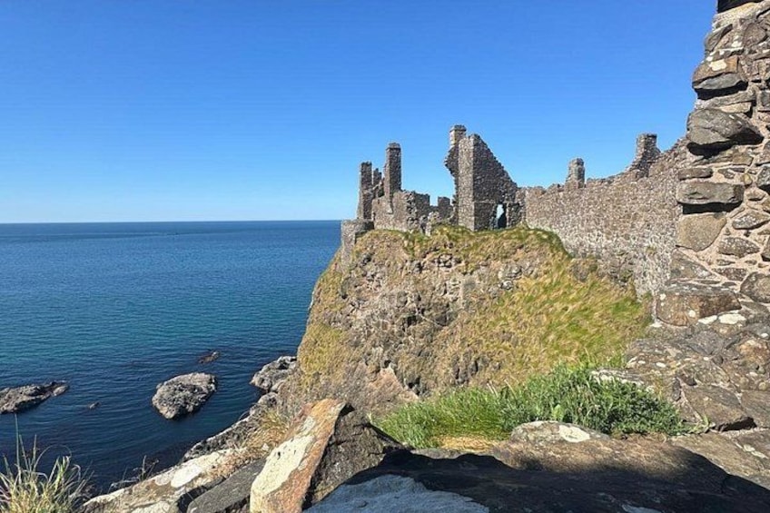Une construction en pierre située sur la côte, avec des ruines, un ciel bleu dégagé et une mer calme. 3