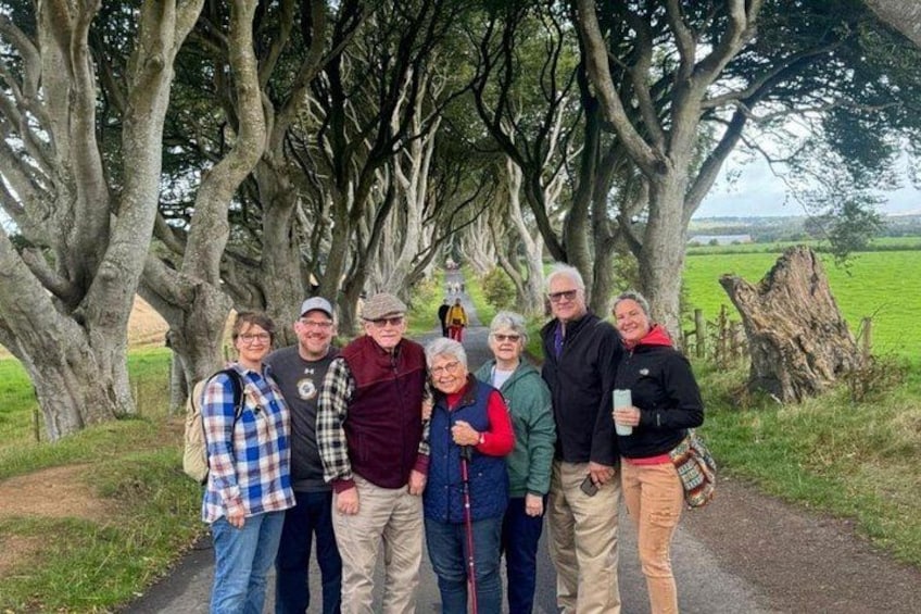 A group of people standing on a path with trees and a grassy field in the background. 2