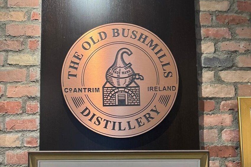 Ein rundes Schild mit dem Text 'The Old Bushmills Distillery' und einer Illustration einer Brennerei. 4