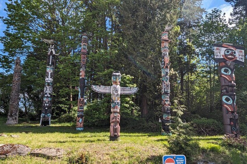 Totem poles with intricate carvings in a forested area. 2