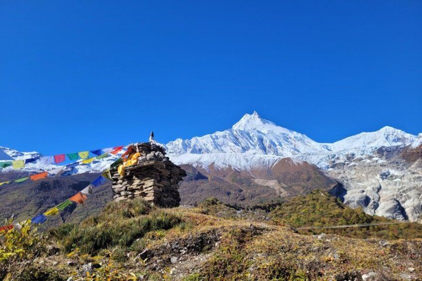 A snow-capped mountain, prayer flags, and a rocky outcrop. 2
