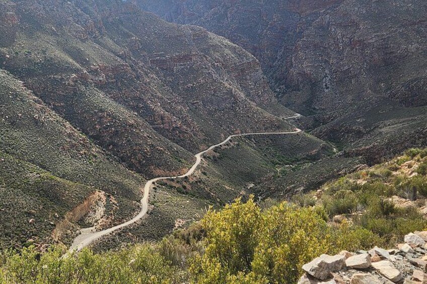 A winding mountain road through a canyon with sparse vegetation. 1