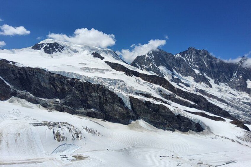 A snow-covered mountain range with rugged peaks and a clear blue sky. 3