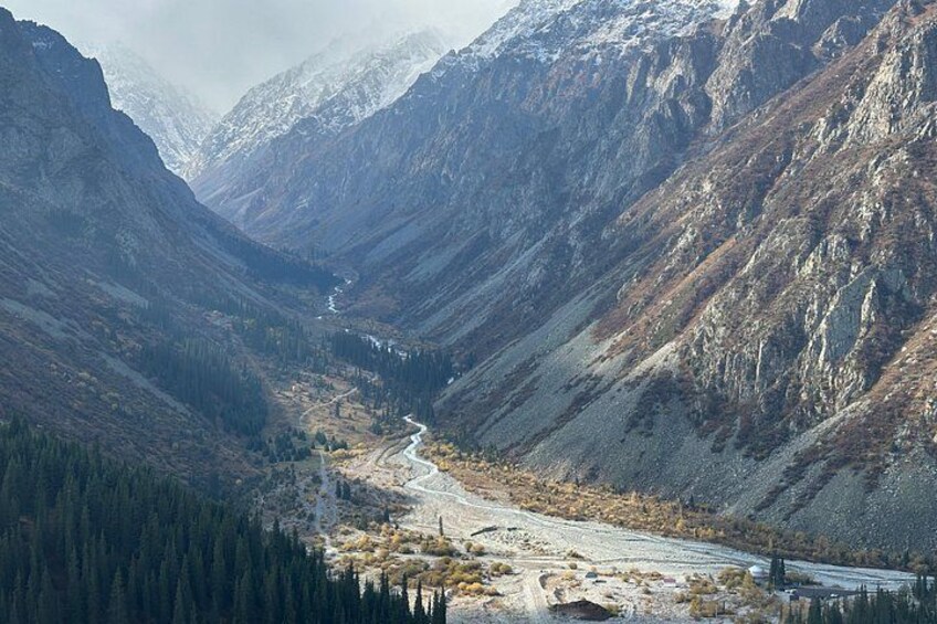 A mountainous landscape with a winding river, dense forests, and snow-capped peaks. 4