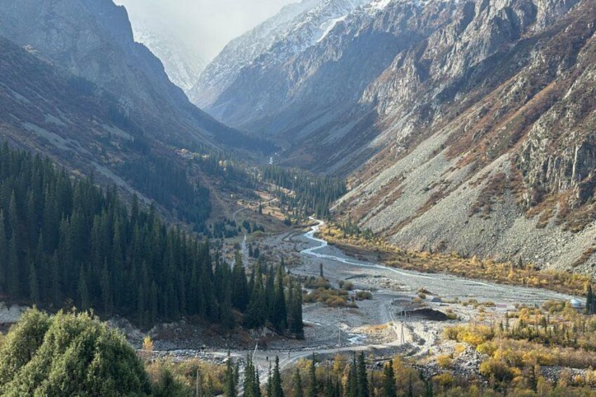A mountainous landscape with a river winding through a valley, surrounded by dense forests and rocky terrain. 3