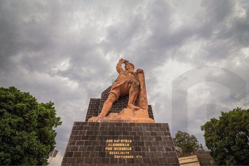A statue of a man with a raised arm on a pedestal with inscriptions. 2
