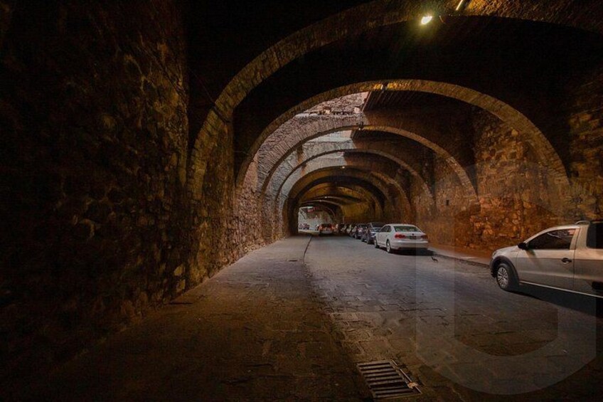A stone tunnel with arched ceilings and a vehicle parked inside. 3