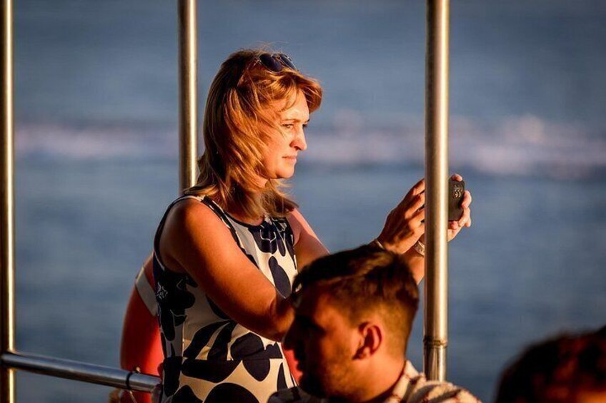 A person taking a photo with a camera, standing on a boat with metal railings, and the ocean in the background. 3