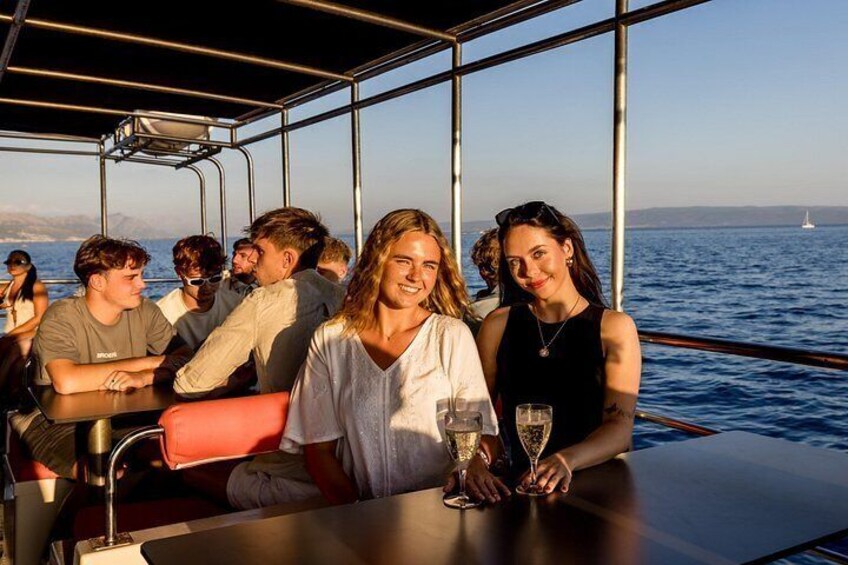 A group of people on a boat with a view of the ocean and a sailboat in the distance. 4