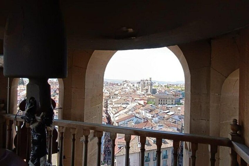A view through an arched window of a cityscape with buildings and a statue. 2
