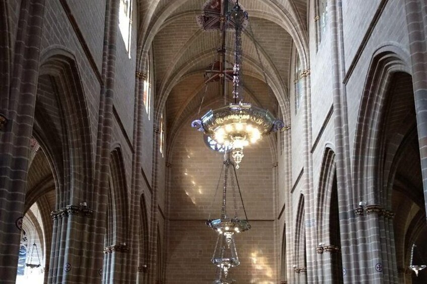 Et katedralinteriør med hvælvede lofter og en stor lysekrone i midten. 3