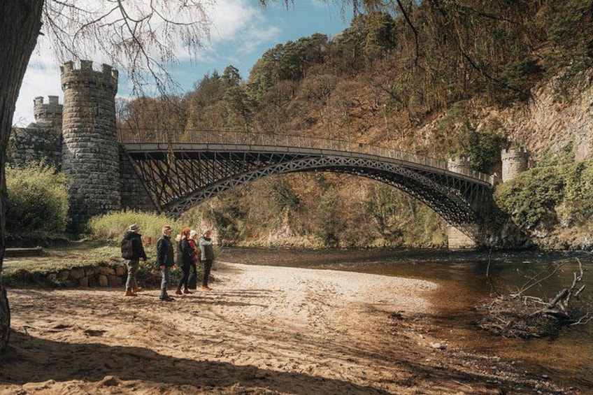 A stone bridge over a river, surrounded by trees and a castle in the background. 3