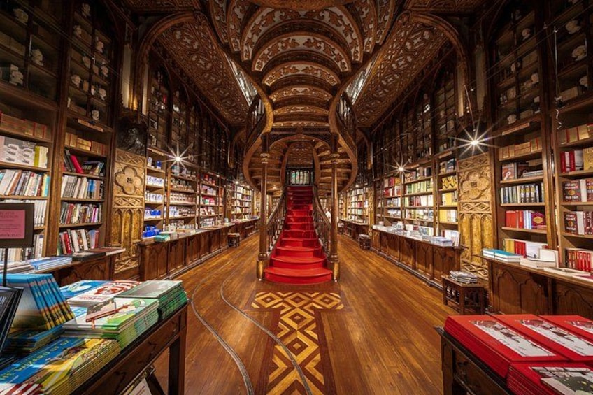 A grand library with ornate wooden bookshelves, a central staircase, and a patterned floor. 4