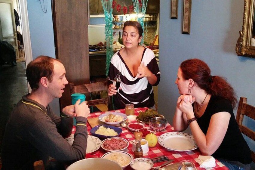 A dining table with various dishes, a person holding a drink, and another person gesturing. 2