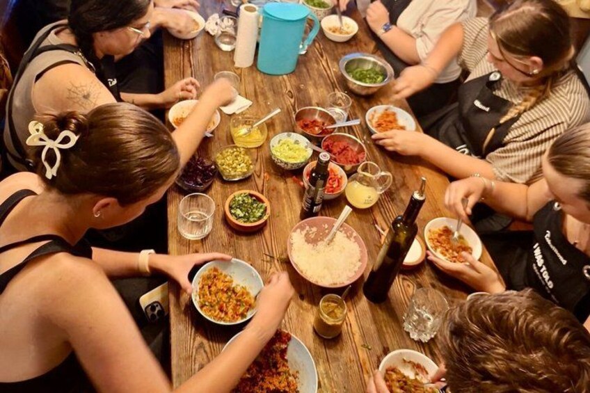 A group of people sitting around a wooden table with various dishes and condiments. 1