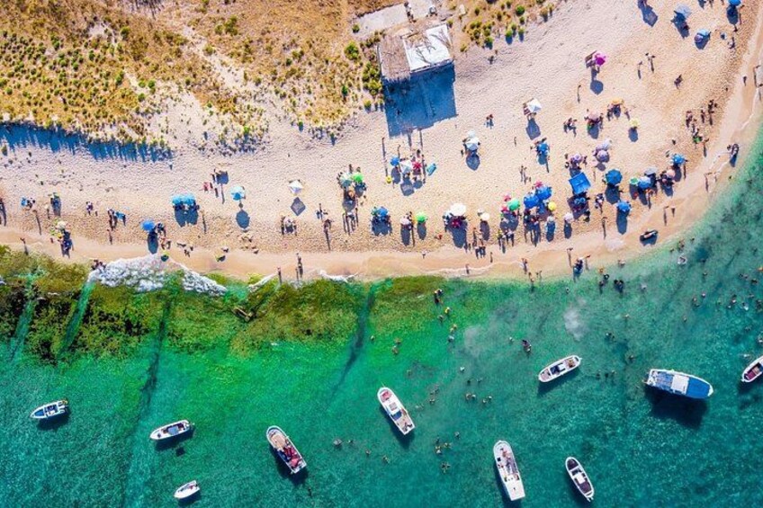 An aerial view of a beach with people, boats, and umbrellas. 1