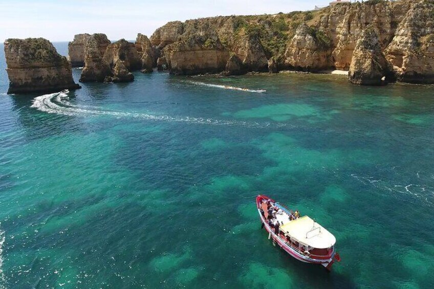 Un bateau navigue près de falaises rocheuses, dans des eaux turquoise et limpides. 4