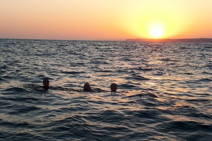 Trois personnes nagent dans l’océan au coucher du soleil. 5