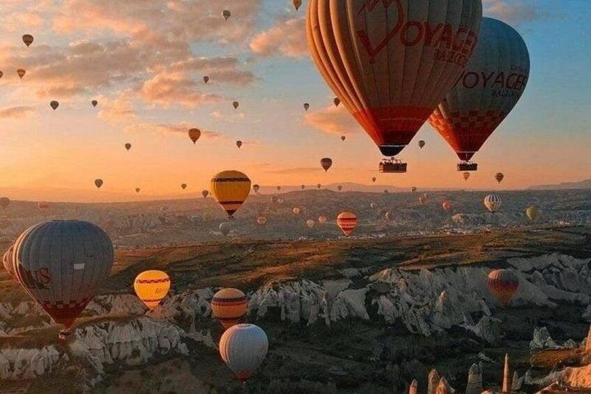 Varmluftsballonger svävar över ett bergigt landskap under en klar himmel. 5