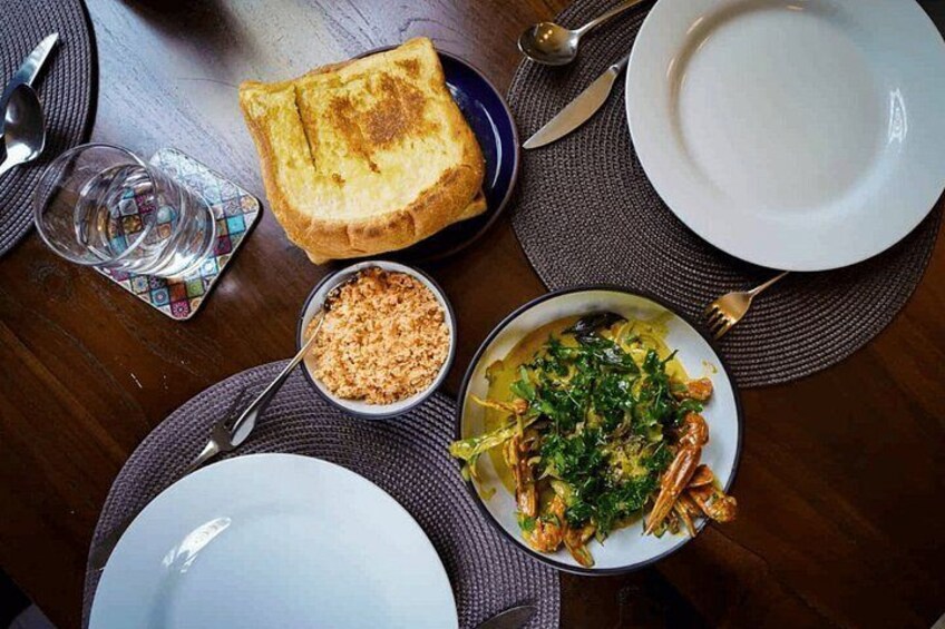 A dining table with plates, a bowl of soup, a piece of toast, and cutlery. 3