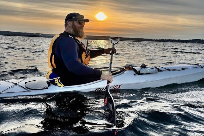 A person kayaking on a body of water during sunset. 2