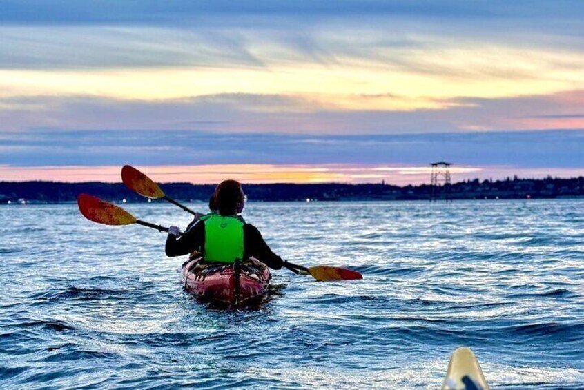 A person kayaking on a body of water during sunset. 1